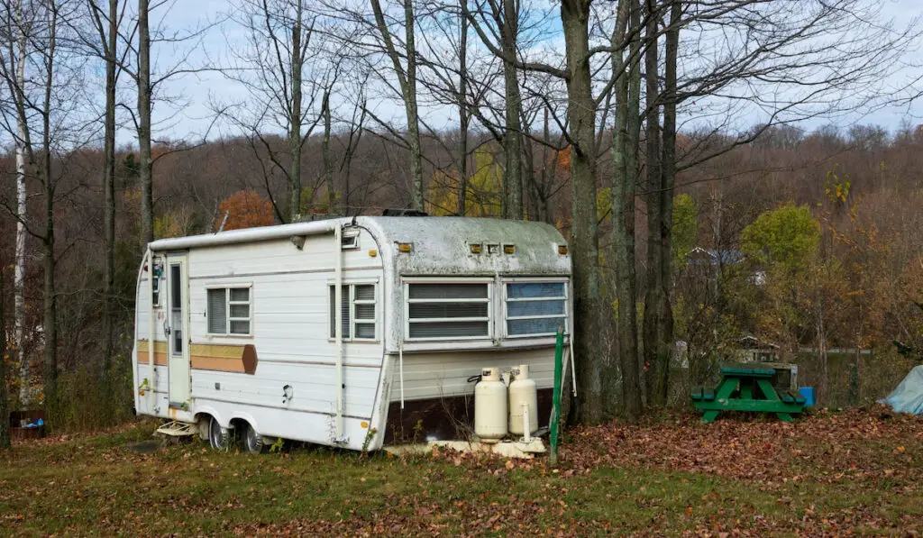 An old RV trailer for camping with two gas tank outside
