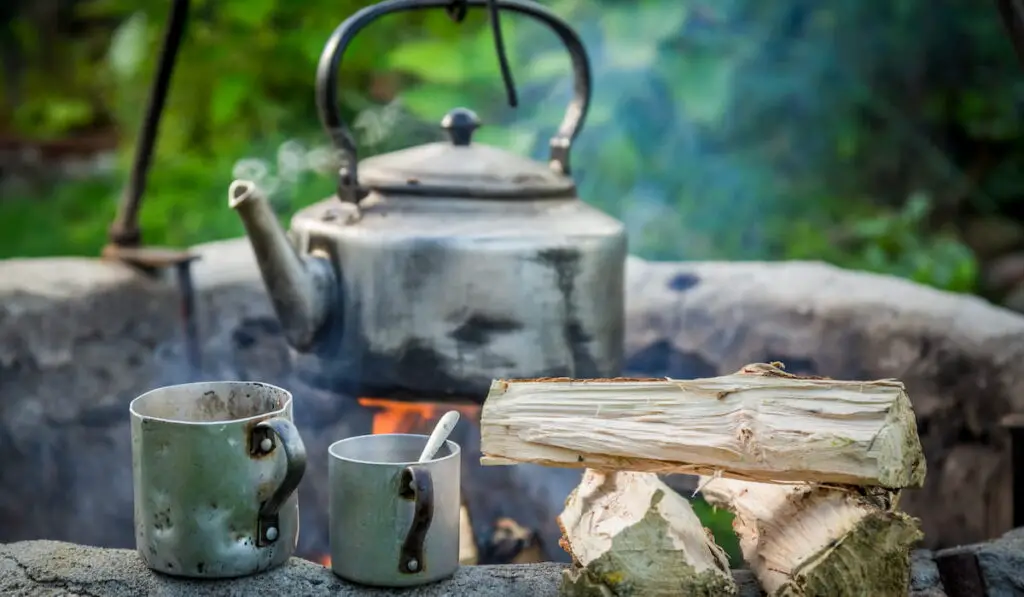 Freshly made coffee with kettle on campfire