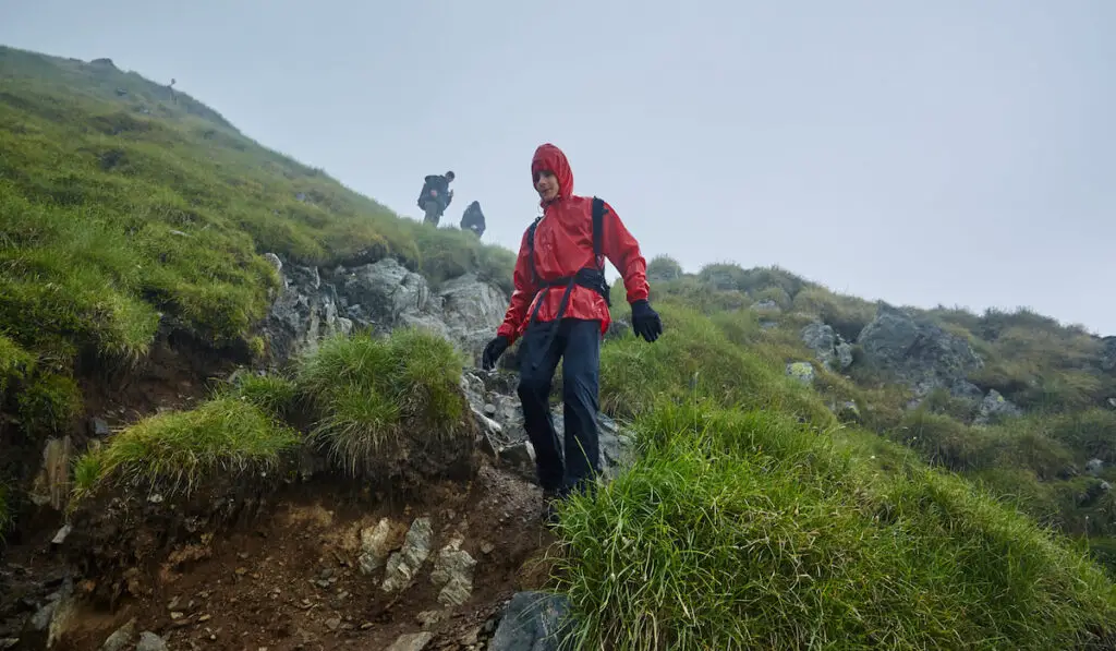 Group of hikers descending on a mountain with raincoats during rain