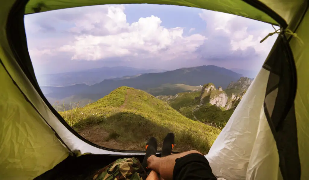 Man Camping and relaxing Lying Inside Tent watching beautiful mountains