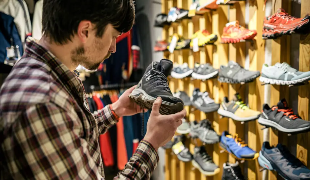 Man choosing hiking boots in sports store