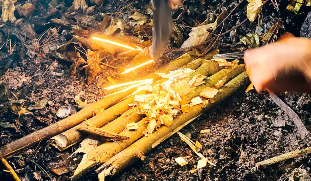Man trying to start a fire in the woods, survival camping concept