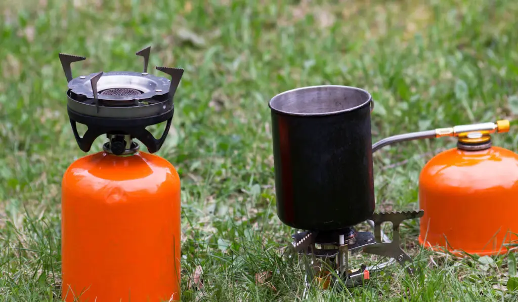 Two camping gas stoves stand on the grass