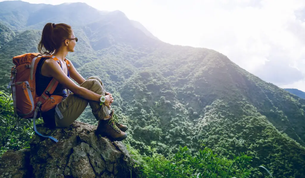 Woman hiker sit on mountain top enjoy the view
