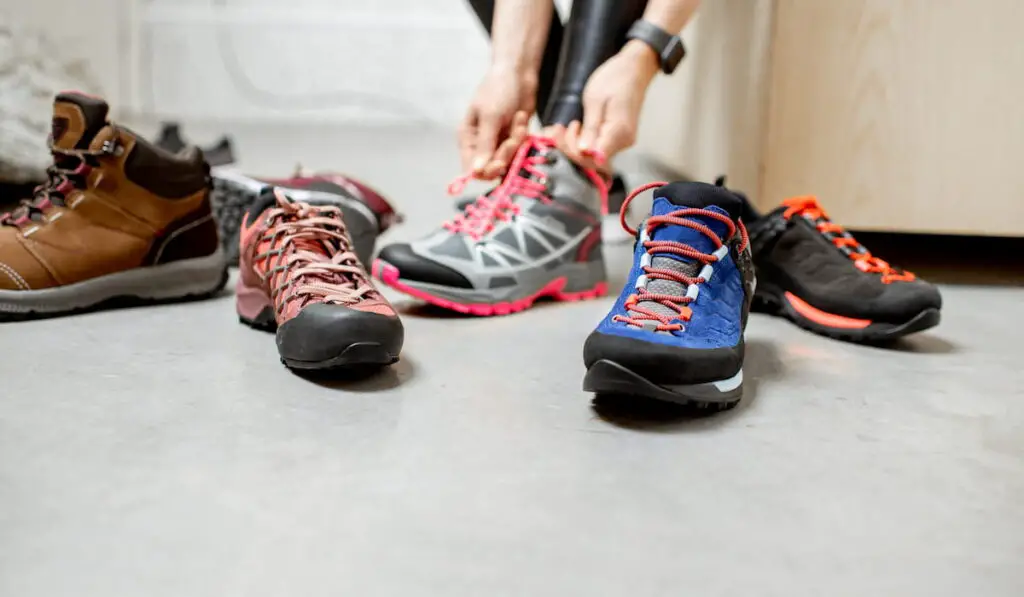 Woman trying different trail shoes for mountain hiking in the sports shop