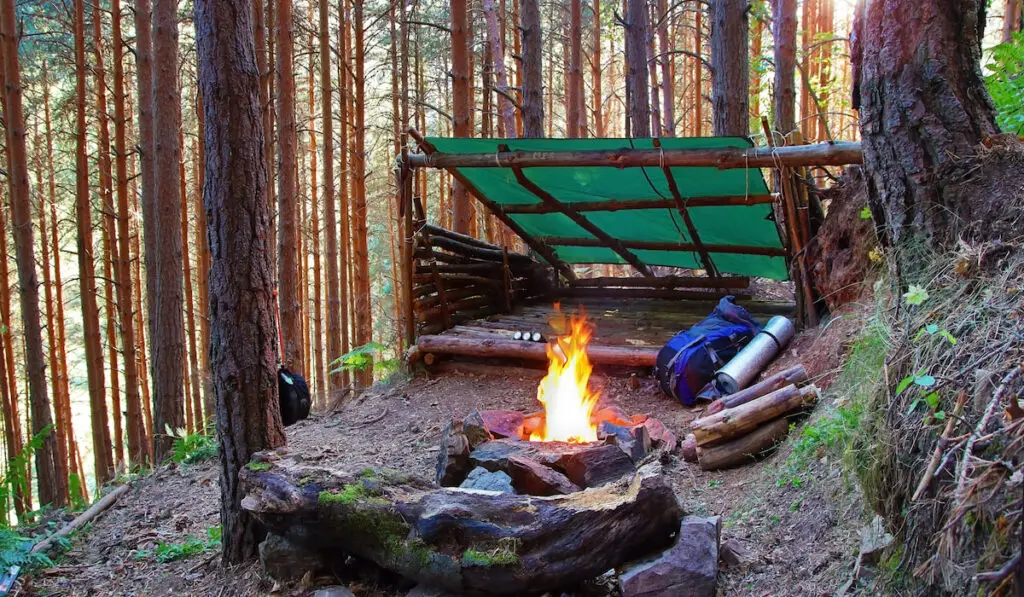 Wooden shelter with a tarp and a fire pit made of stones
