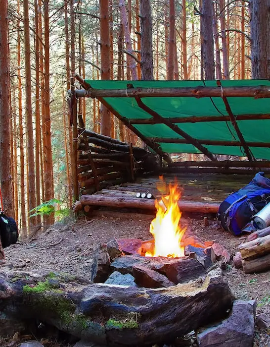 Wooden-shelter-with-a-tarp-and-a-fire-pit-made-of-stones