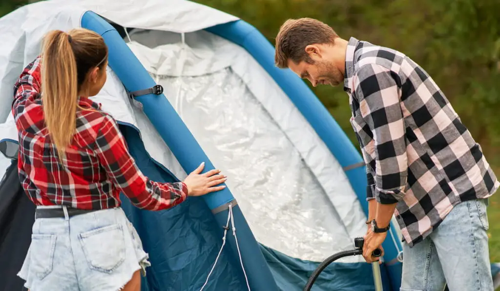Young couple having fun on camping setting up tent
