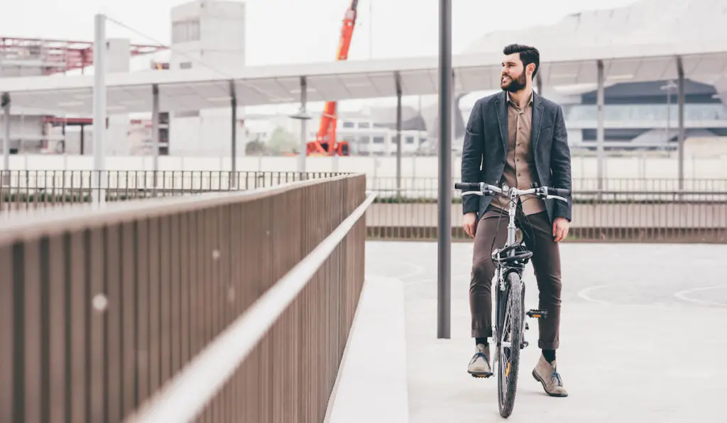 bearded businessman posing outdoor riding bike