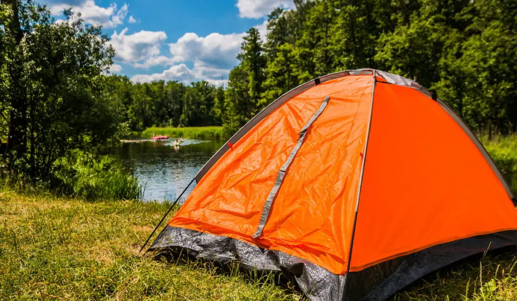 orange tent set up near the lake 
