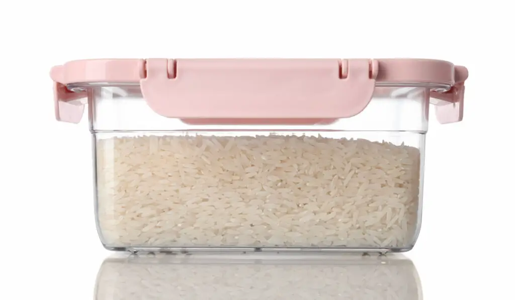 raw rice in a glass container on white background