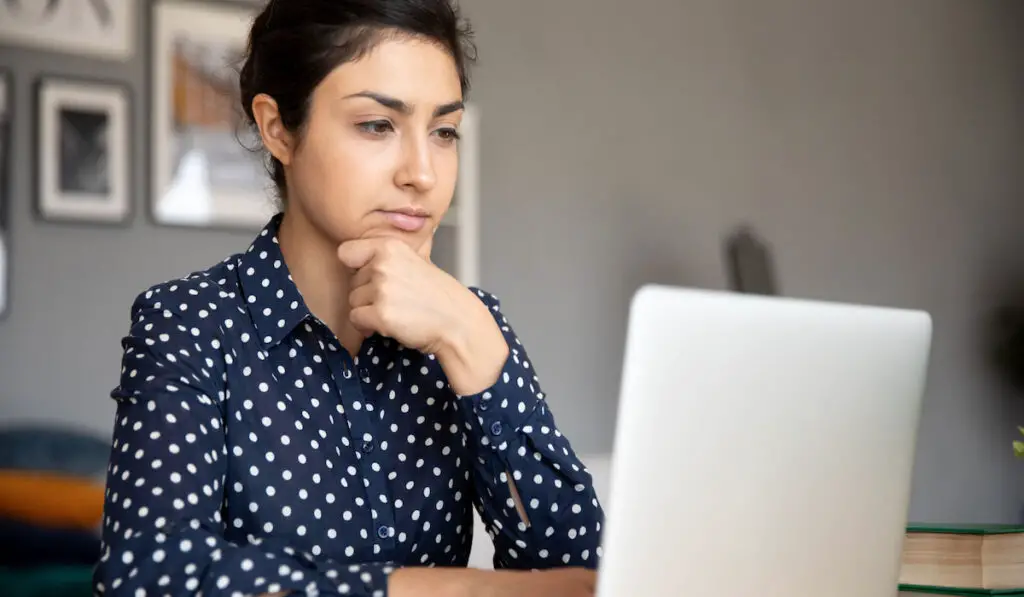 woman researching on her laptop, with thinking face