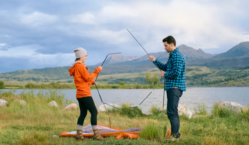 Couple in rural setting, putting up tent
