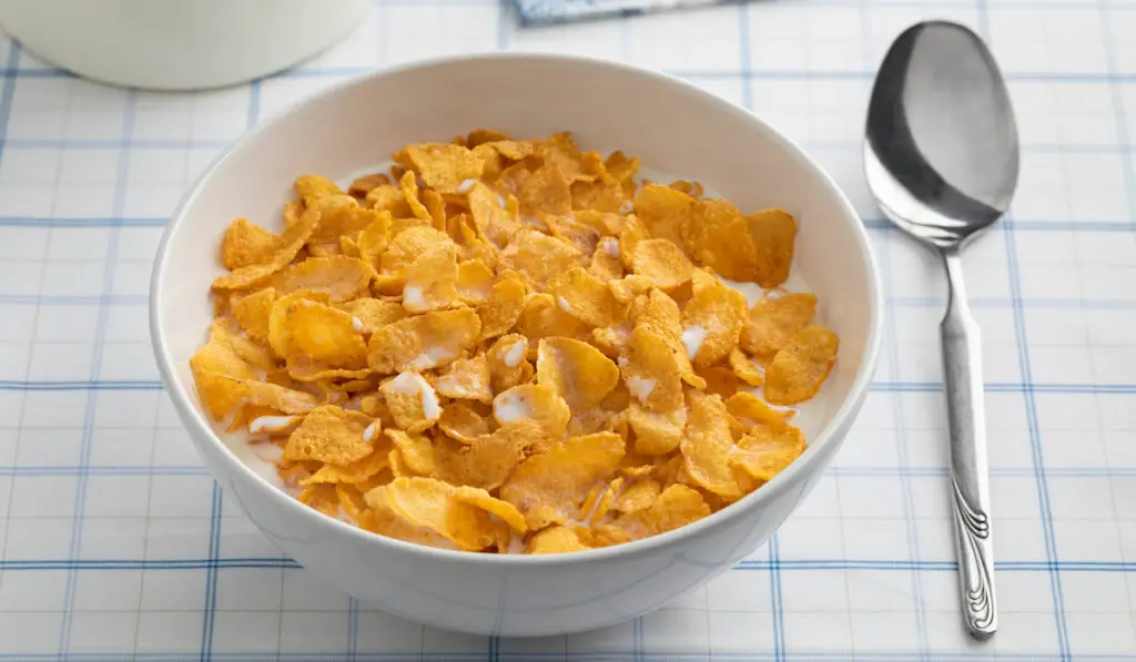 Bowl with cornflakes and milk on the table